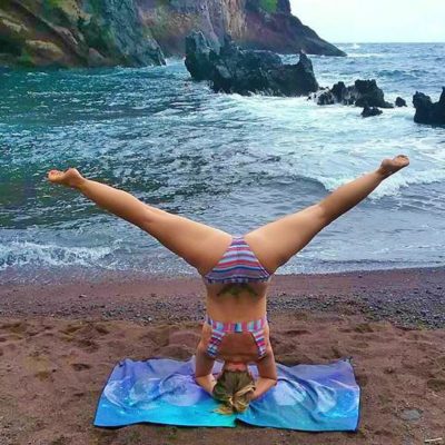 girl doing headstand by ocean