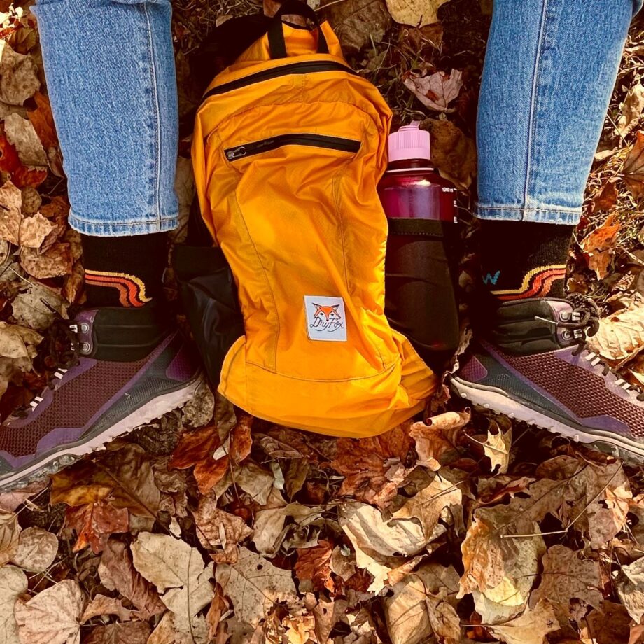orange backpack laying in leaves