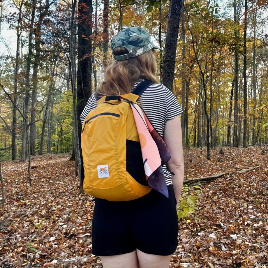 orange compact backpack from front on woman in woods